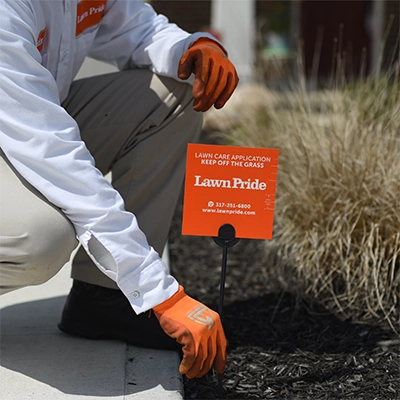 Lawn Pride Professional placing sign on the lawn.