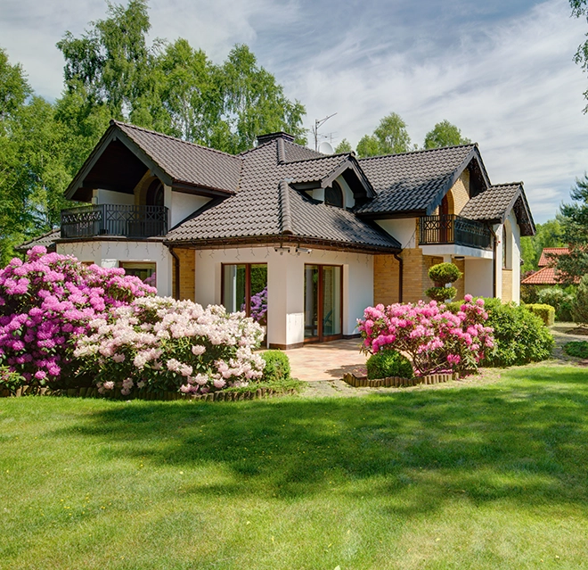 A house with a lawn, trees, and sky.