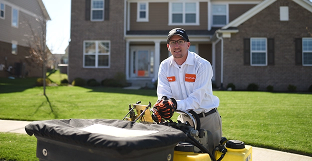 A worker operating a lawn mower on a lawn.