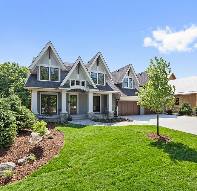 A house with a lawn, trees, and sky.