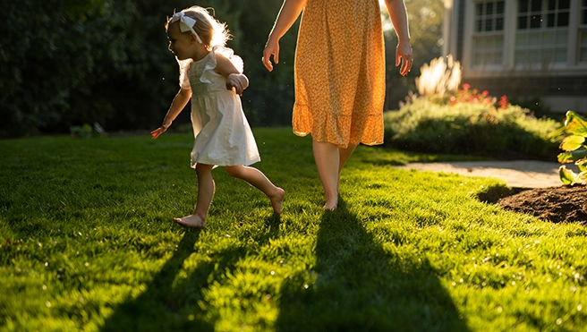 A woman and a child walk through a back yard.