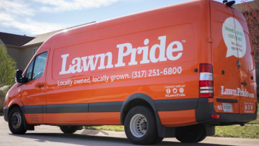 An orange Lawn Pride van is parked on a street.